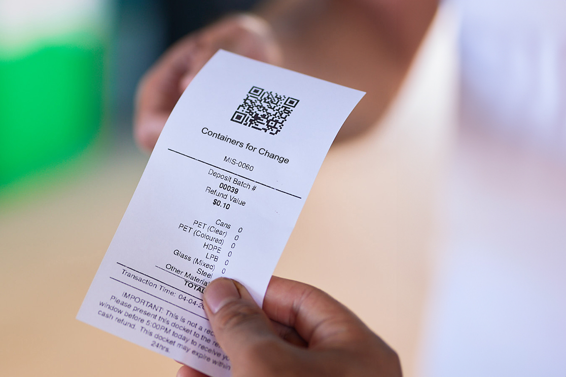 a person holding a tablet passing a reciept through a car window